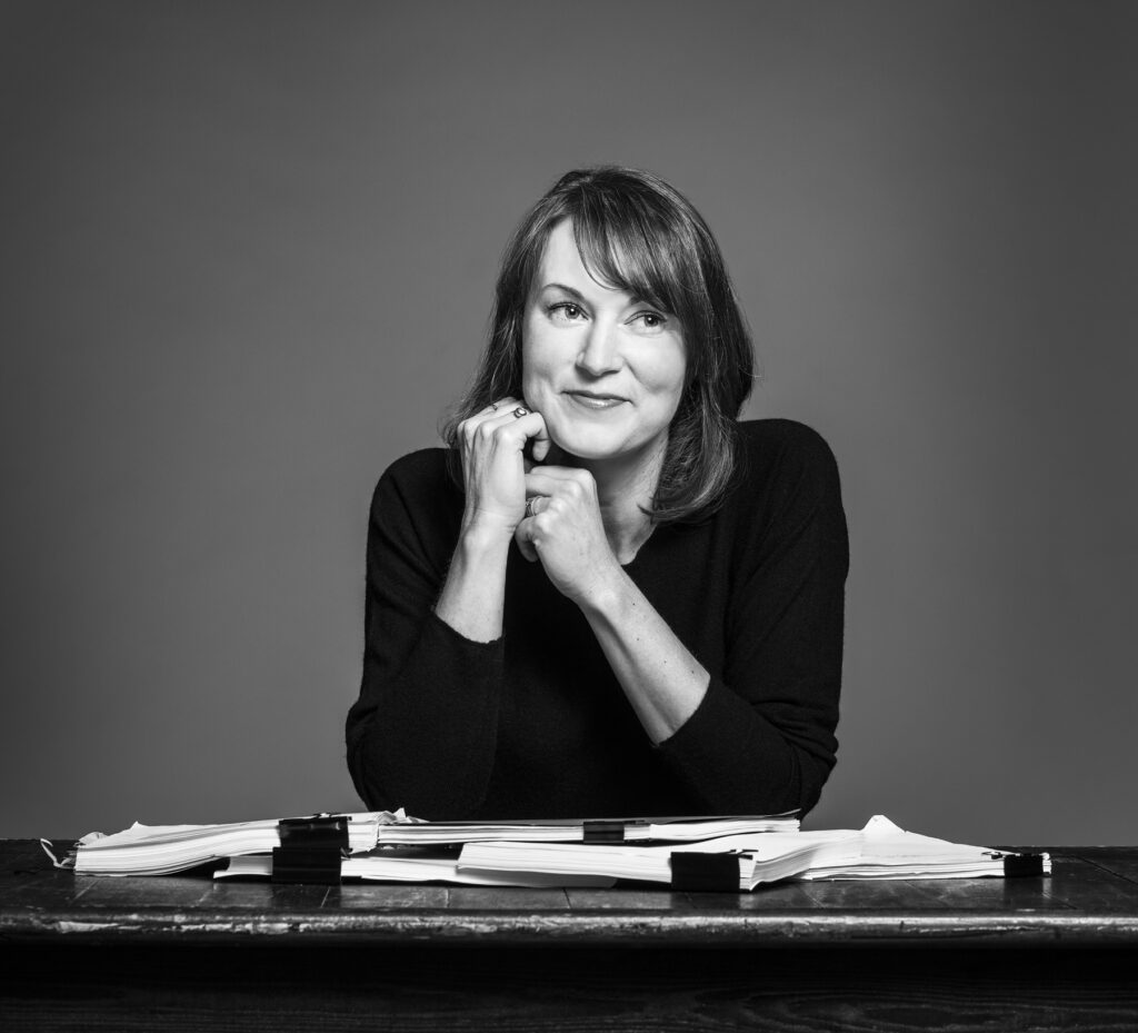 A black and white image of a woman at a desk smiling