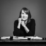 A black and white image of a woman at a desk smiling